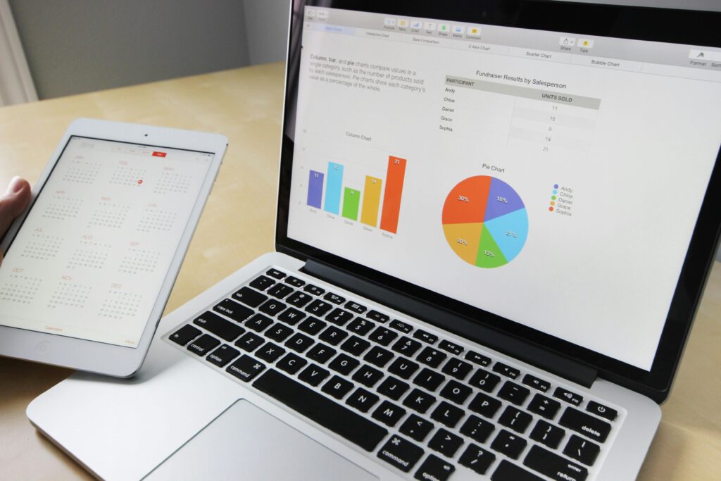 Laptop displaying charts and graphs with tablet calendar for data analysis and planning.